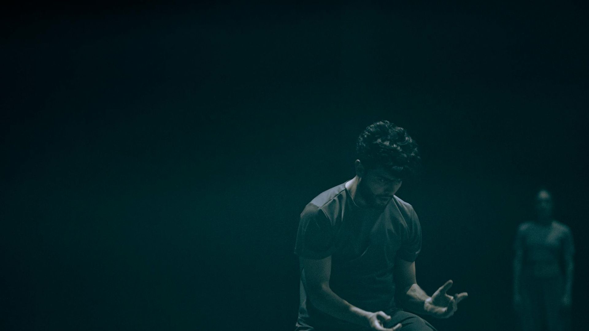 Person performing a fluid cardio movement in a minimalist dark room.